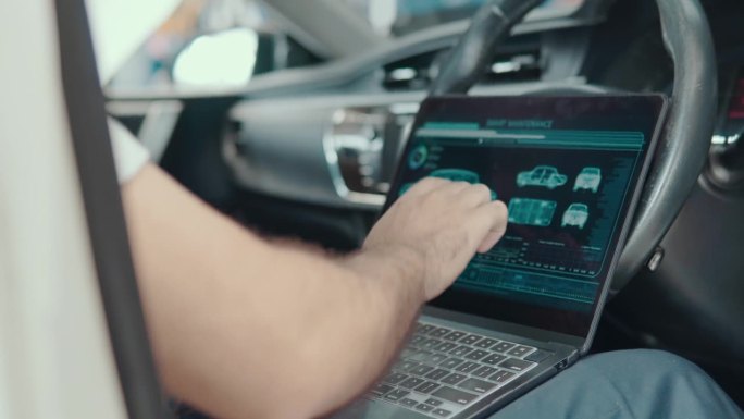 汽车维修技师使用装有汽车诊断软件的笔记本电脑。汽车电子诊断应用。