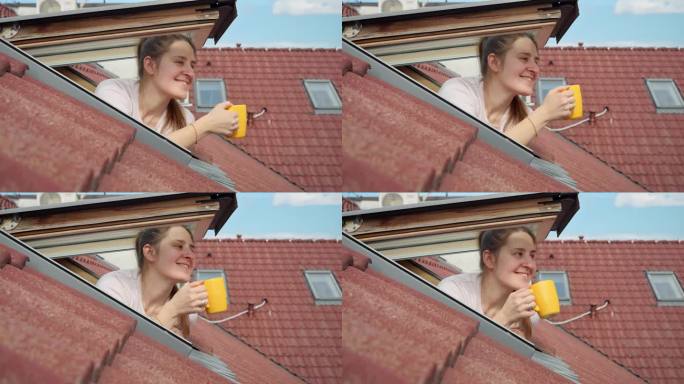 快乐微笑的女人打开阁楼的窗户，早上喝茶或喝咖啡。她正在欣赏城市的景色，看着古老的欧洲小镇的红瓦屋顶