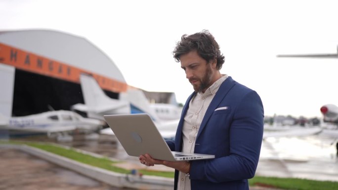 一个中年商人在机场机库使用笔记本电脑的照片