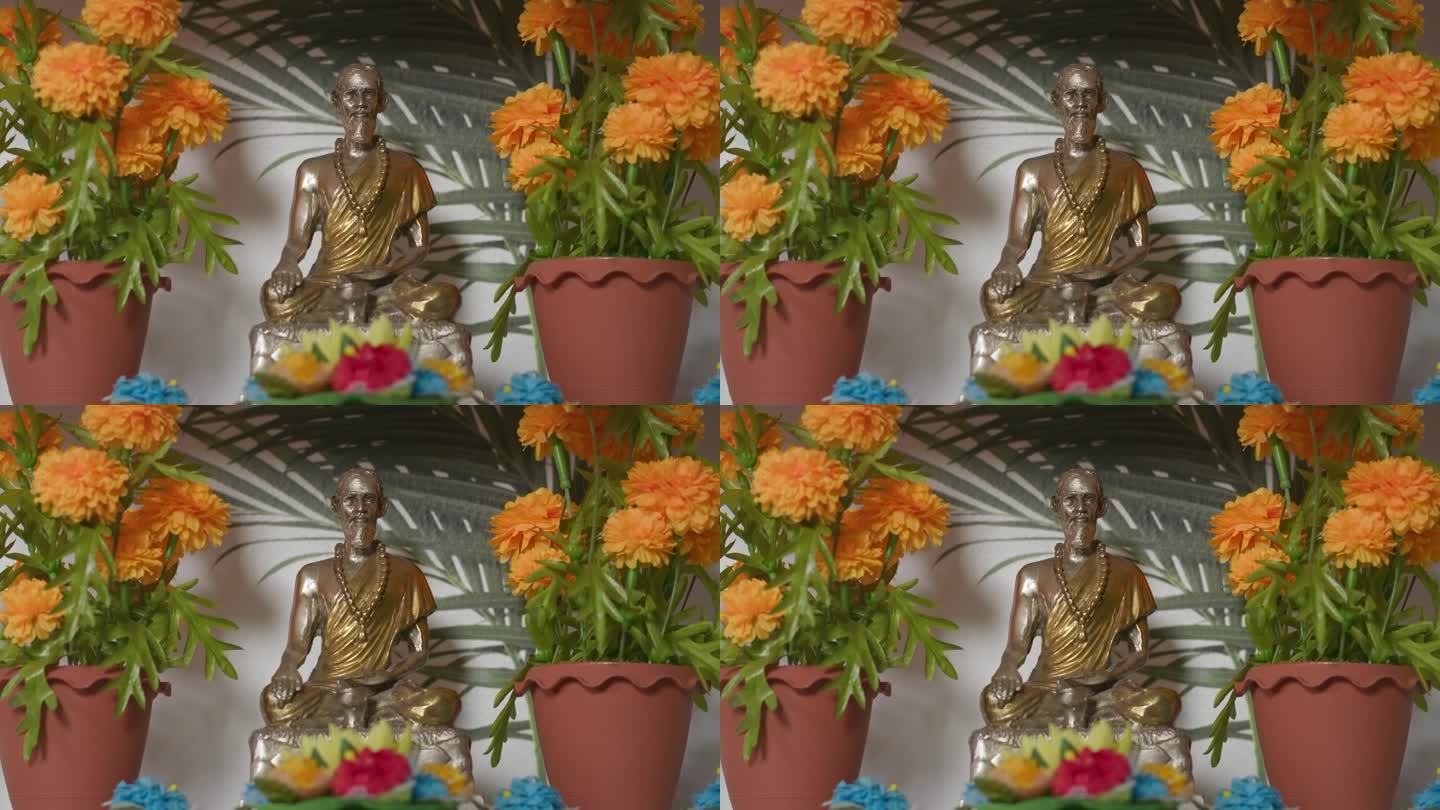 架子上的佛像在橙色的花朵之间
