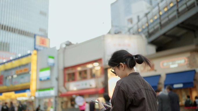 快乐的女游客站着用智能手机给日本城市的美丽建筑拍照。