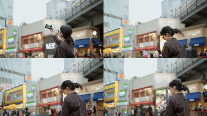 快乐的女游客站着用智能手机给日本城市的美丽建筑拍照。
