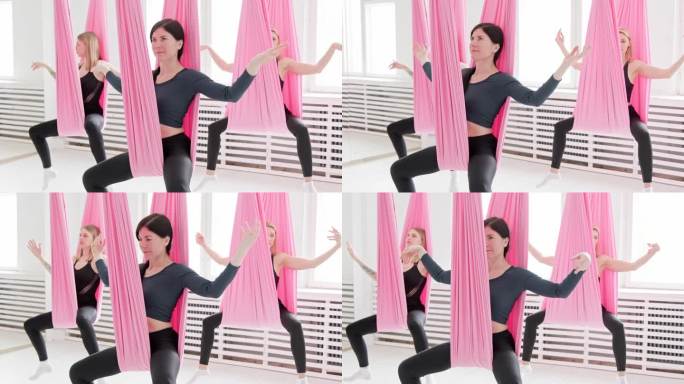 年轻健康的女性在室内空中瑜伽吊床上摇摆。女性放松。