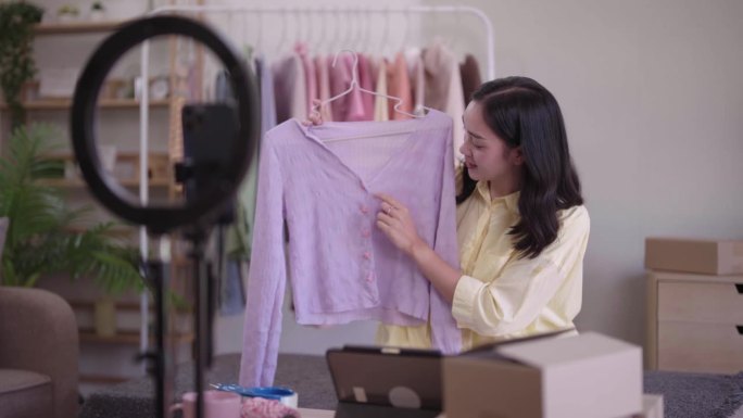 年轻的亚洲女士时装展示二手服装产品呈现细节录制视频直播在家办公室创业小企业企业家中小企业电话营销仓库