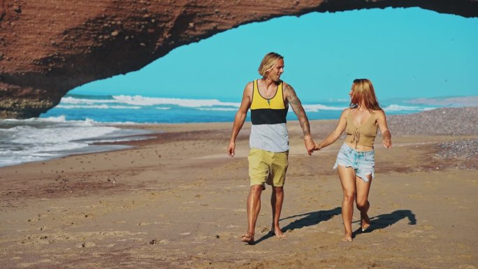 一对情侣幸福地手牵手沿着宁静的沙滩沙滩漫步