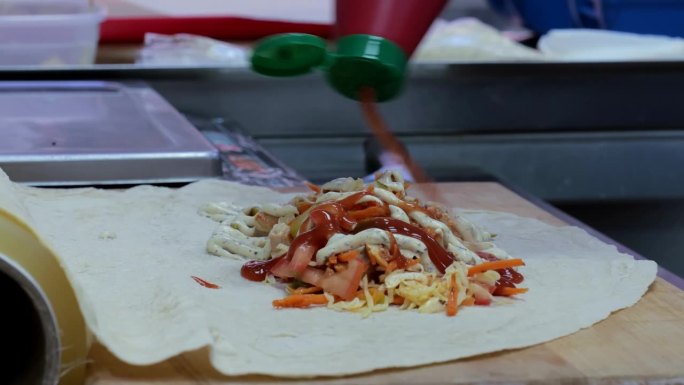 沙瓦玛皮塔饼，沙瓦玛皮塔饼蔬菜炒土豆白菜洋葱，皮塔饼烹饪沙瓦玛的过程特写，烹饪钳把蔬菜放在皮塔饼上。