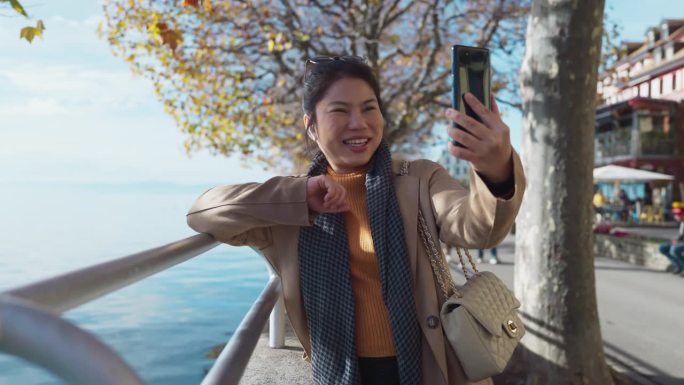 微笑的亚洲女性独自旅行者快乐地分享她精彩的旅行经历，视频通话，与朋友聊天，家庭旅行视频博主，在瑞士韦