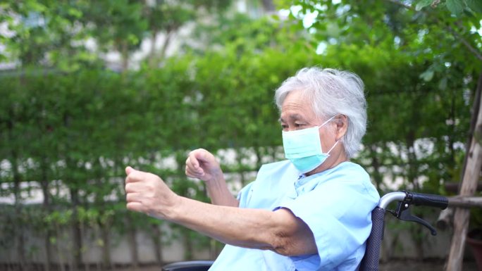 医生帮助亚洲老年病人在轮椅上运动，在公园快乐。