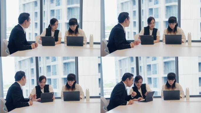 亚洲商人在现代办公空间与同事们指着屏幕交谈。