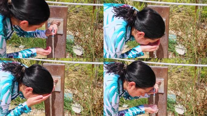 一位妇女用公共泉水里的凉水洗脸