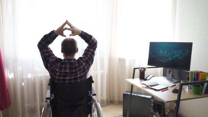 一位坐在轮椅上的残疾工人在电脑前工作。有特殊需求和工作理念的上进心强的人。