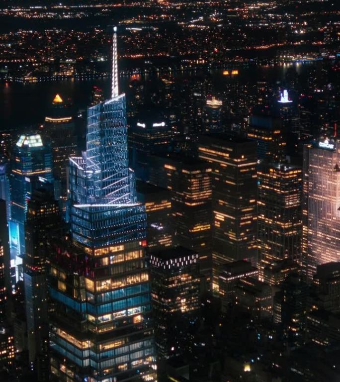 垂直屏幕:办公楼夜间航拍画面。房间里亮着灯，在纽约工作的商人和经理。直升机俯瞰曼哈顿的夜景