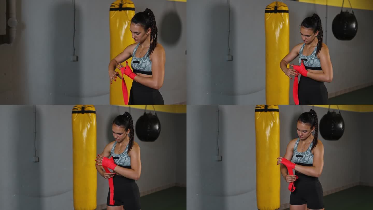 一位身穿运动服的年轻女拳击手在手上缠上防护绷带，准备进行拳击训练