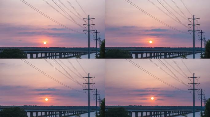 红黄色的太阳球从横跨河流的公路桥上的电线杆后面的薄云中升起，时间流逝