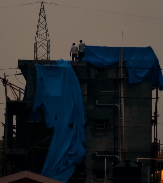 男人们在施工中使用防水油布防雨。视频素材垂直4K