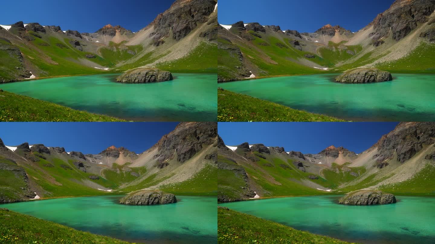 航拍电影无人机冰湖盆地西尔弗顿岛湖水蓝色清澈的水高山苔原令人惊叹的山脉野花仲夏白天蓝天美丽缓慢的盘向