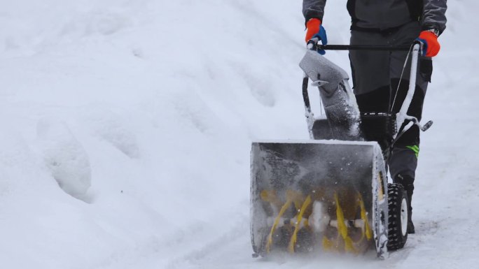 移动吹雪机除雪过程，大雪后的冬天，工人穿着工作服在街上用吹雪机除雪，慢动作