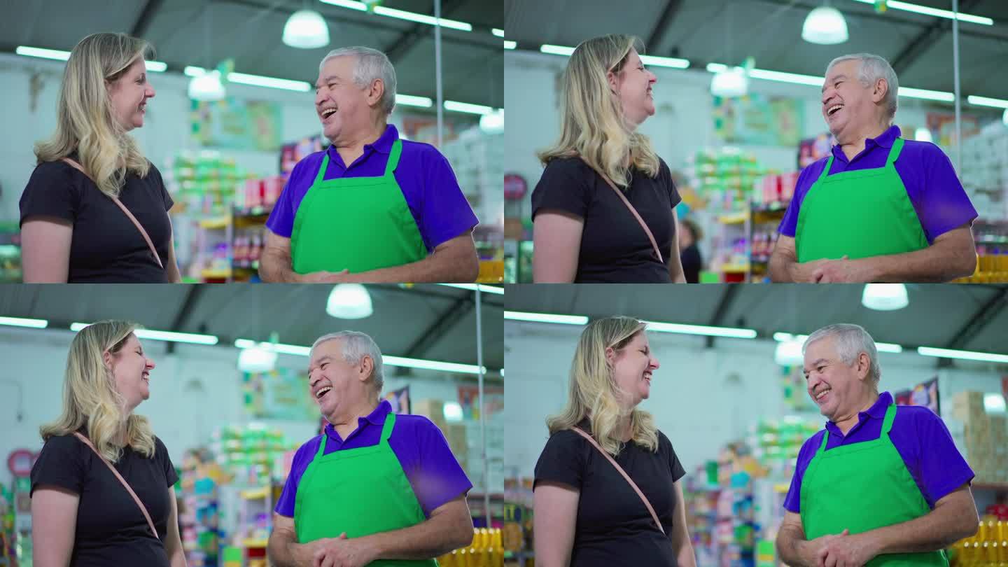 站在超市里的白人老年职员和女顾客谈笑风生。年长的员工与客户交谈