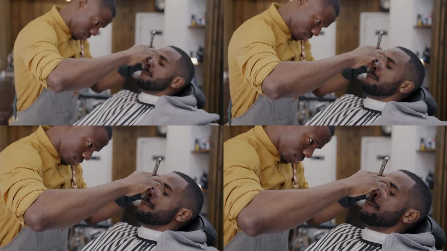 非裔美国人在理发店用锋利的剃刀修剪胡须的放大镜头