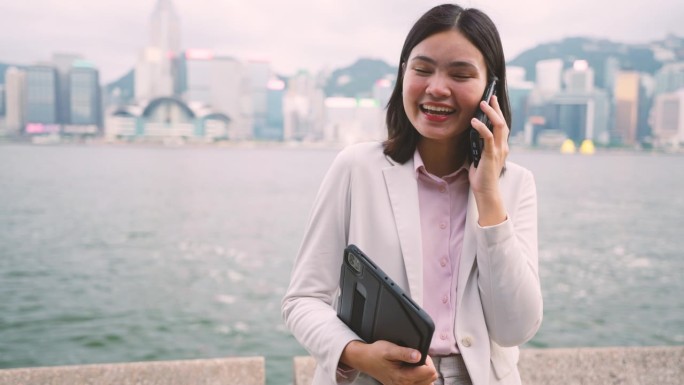 走在香港商业中心中心的女商人用你的手机来协调工作。