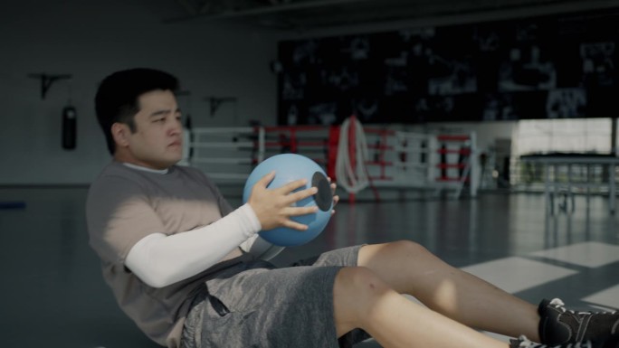 图为亚洲运动员在室内健身房里进行腹部仰卧起坐的高强度训练