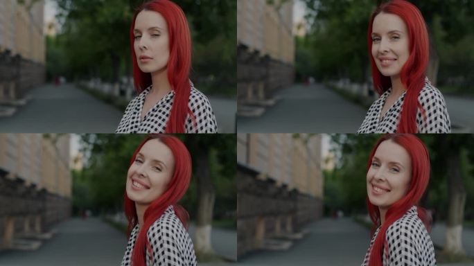 一个染红头发的漂亮年轻女子的慢动作肖像转向镜头，微笑着在城市户外调情
