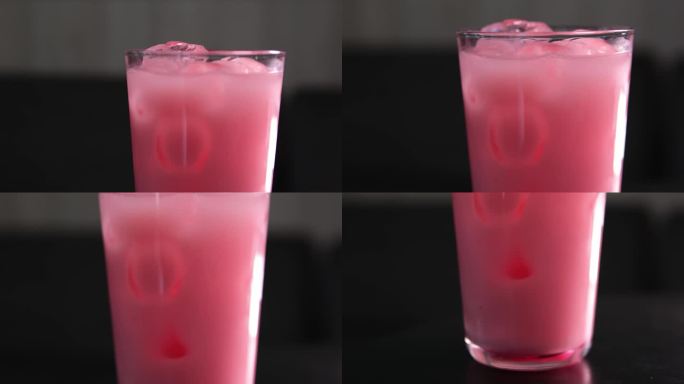 草莓牛奶在一个杯子与条纹纸吸管隔离在黑色背景