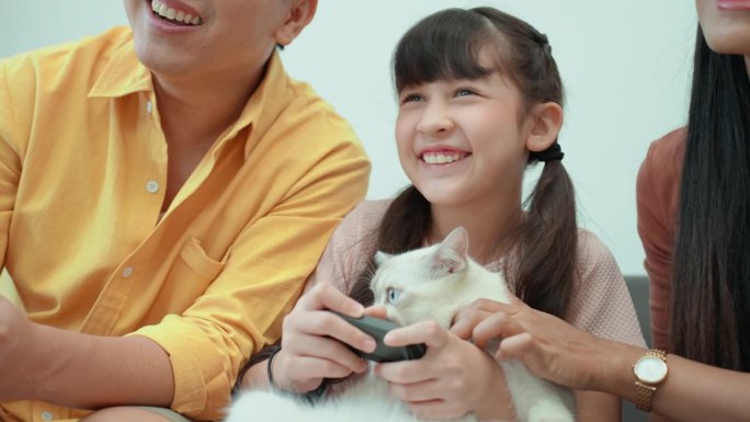 快乐的亚洲家庭，爸爸和小孩一起玩电子游戏休息。印度中年母亲一边为猫加油，一边抚摸着猫。