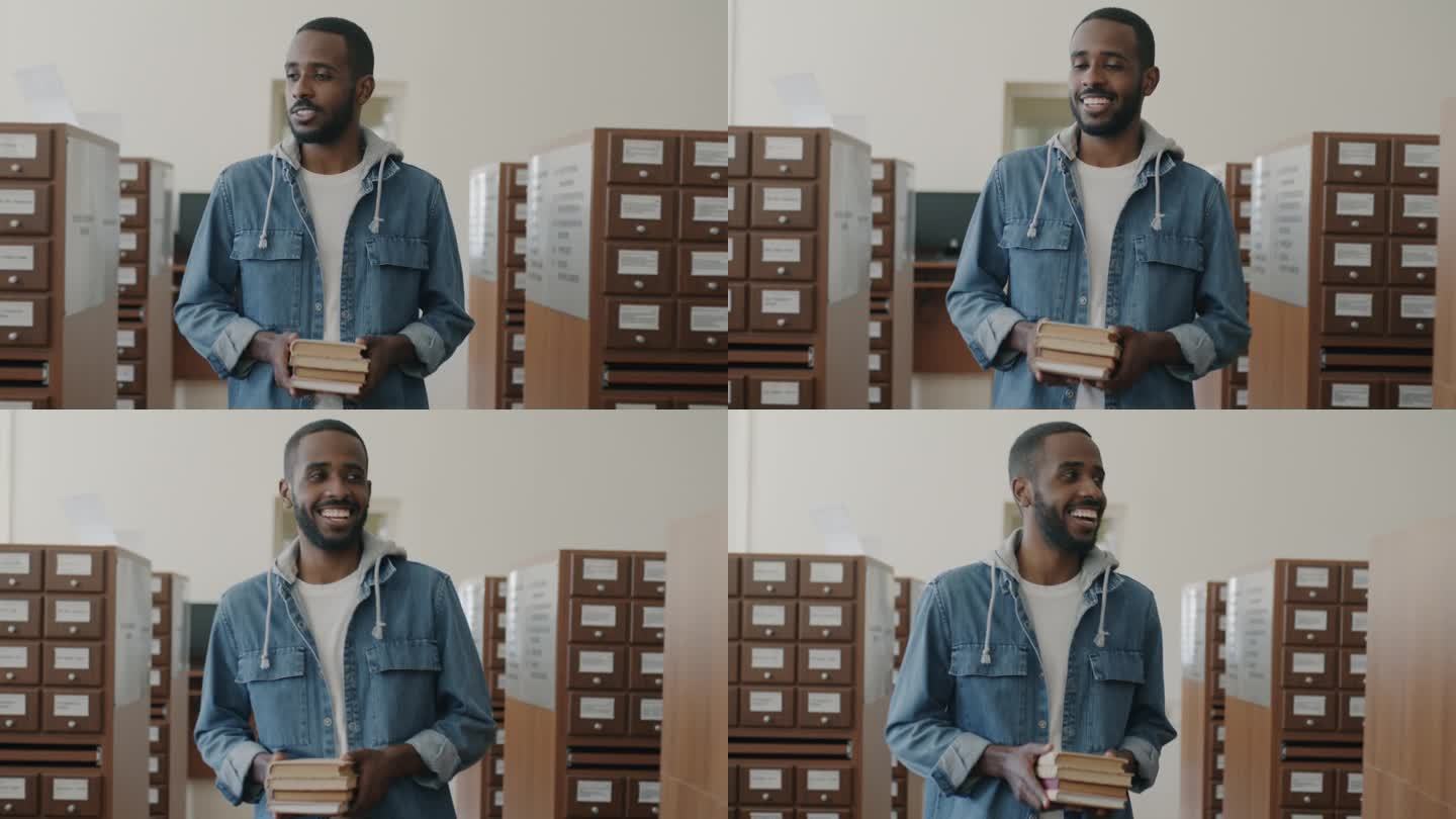 一个快乐的非洲裔美国人，手里拿着书，微笑着走在图书馆大厅里