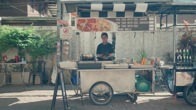 亚洲女厨师烹饪美味的传统泰式炒面在曼谷街头市场厨房-泰国街头食品。