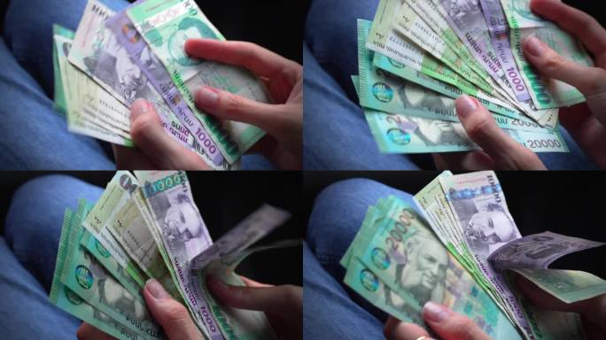 一名妇女拿出亚美尼亚纸币，拿在手里(特写)
