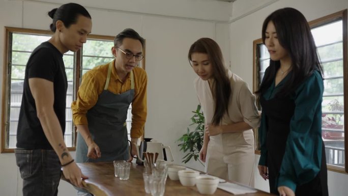 亚裔华裔男咖啡师舀咖啡渣清洗杯饮范围，从桌上的陶瓷杯上撇去咖啡渣-库存视频