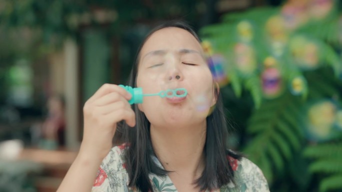 快乐时刻:亚洲男孩和妈妈在公园吹泡泡创造回忆-快乐的户外家庭时光