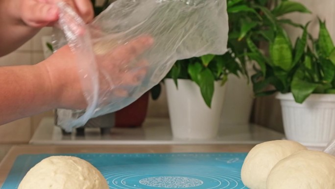 一名妇女将光滑的酵母面团放入玻璃纸袋中打样。松软的面包