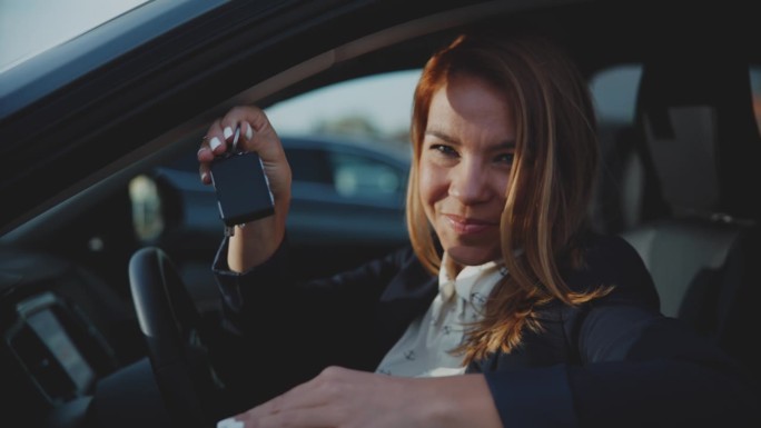 画像中快乐的女人拿着车钥匙站在新车窗口