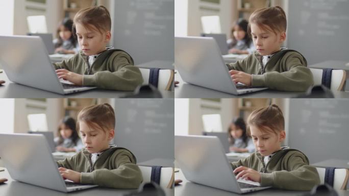 小学生坐在书桌前用笔记本电脑做作业