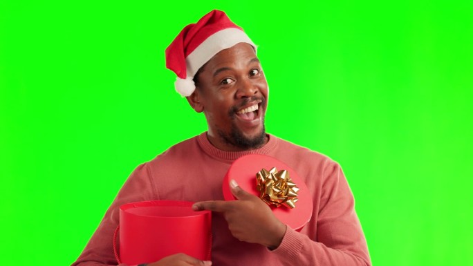 惊喜，绿幕和一个男人带着圣诞礼盒和圣诞老人的帽子，一脸震惊地出现在演播室里。快乐，现在和肖像的非洲男