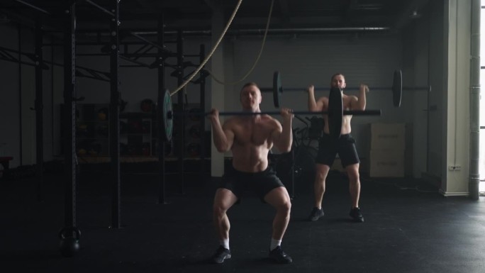 男性健身模特在健身房训练，两个强壮的男人举杠铃，高强度训练
