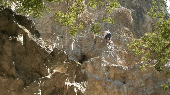 低角度观察:领队攀登者爬上石灰岩岩壁并安装保护装置