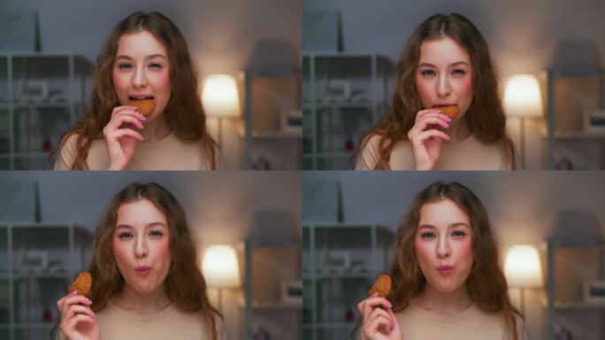 年轻女子吃甜食和看镜头近距离的肖像。现代人吃燕麦饼干在快乐中放松。独自一人的饥饿感和食欲与脆脆的款待