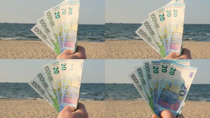 一名无法辨认的女子在沙滩上展示一堆欧元现钞。概念理财为度假攒钱。旅游度假费用。额外的钱