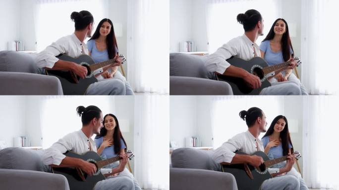 幸福的情侣在家里客厅的沙发上唱着歌弹着吉他