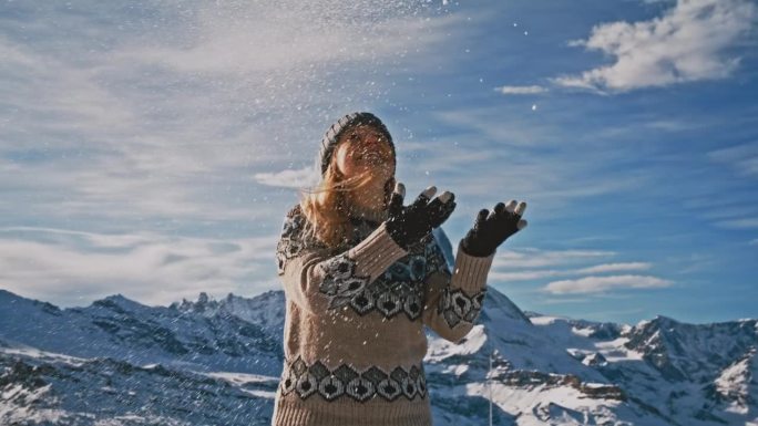 一个女人向空中抛雪，背景是马特洪峰
