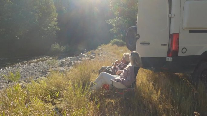 成熟的夫妇在露营车旁喝酒放松