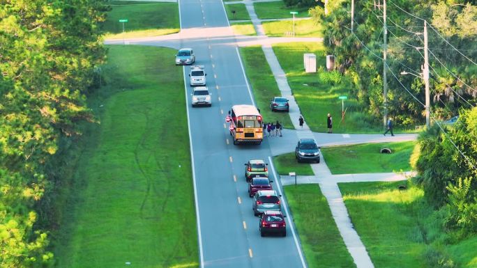 清晨，标准的美国黄色校车在乡村小镇街道上接送孩子们上课。美国的公共交通