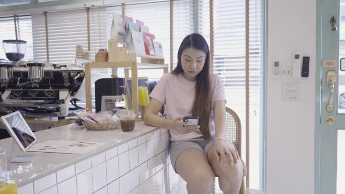 一位年轻的亚洲女子大清早坐在吧台边喝咖啡