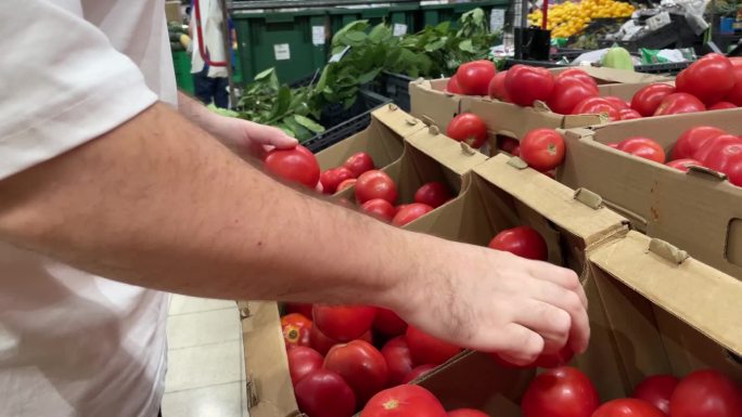 选择蔬菜，男人的手在超市的蔬菜部选择成熟的新鲜西红柿，在网上购物，在商店卖食物