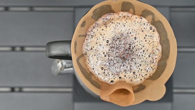 咖啡师用滤纸将热水倒在咖啡粉上，制成滴滤咖啡。