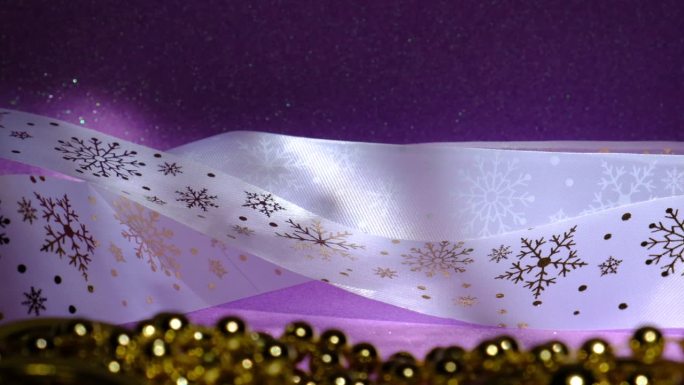 圣诞和新年装饰，迷离的金色首饰和雪花图案缎带，淡紫色，复制空间为呈现，漏光，大气的心情，豪华的婚礼背