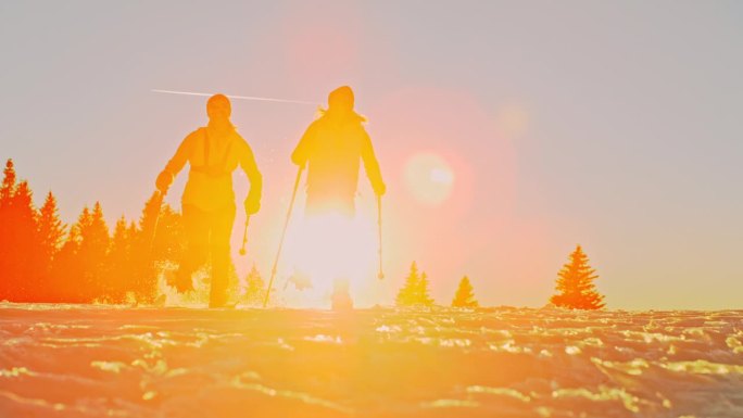 日落时分，两名女徒步者穿着雪鞋在雪地上奔跑